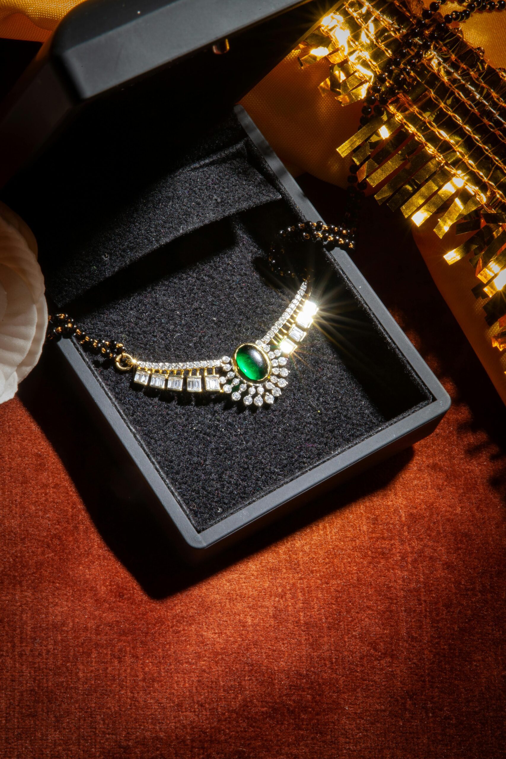A luxurious emerald necklace with diamonds displayed in an open black jewelry box, ready for gifting.