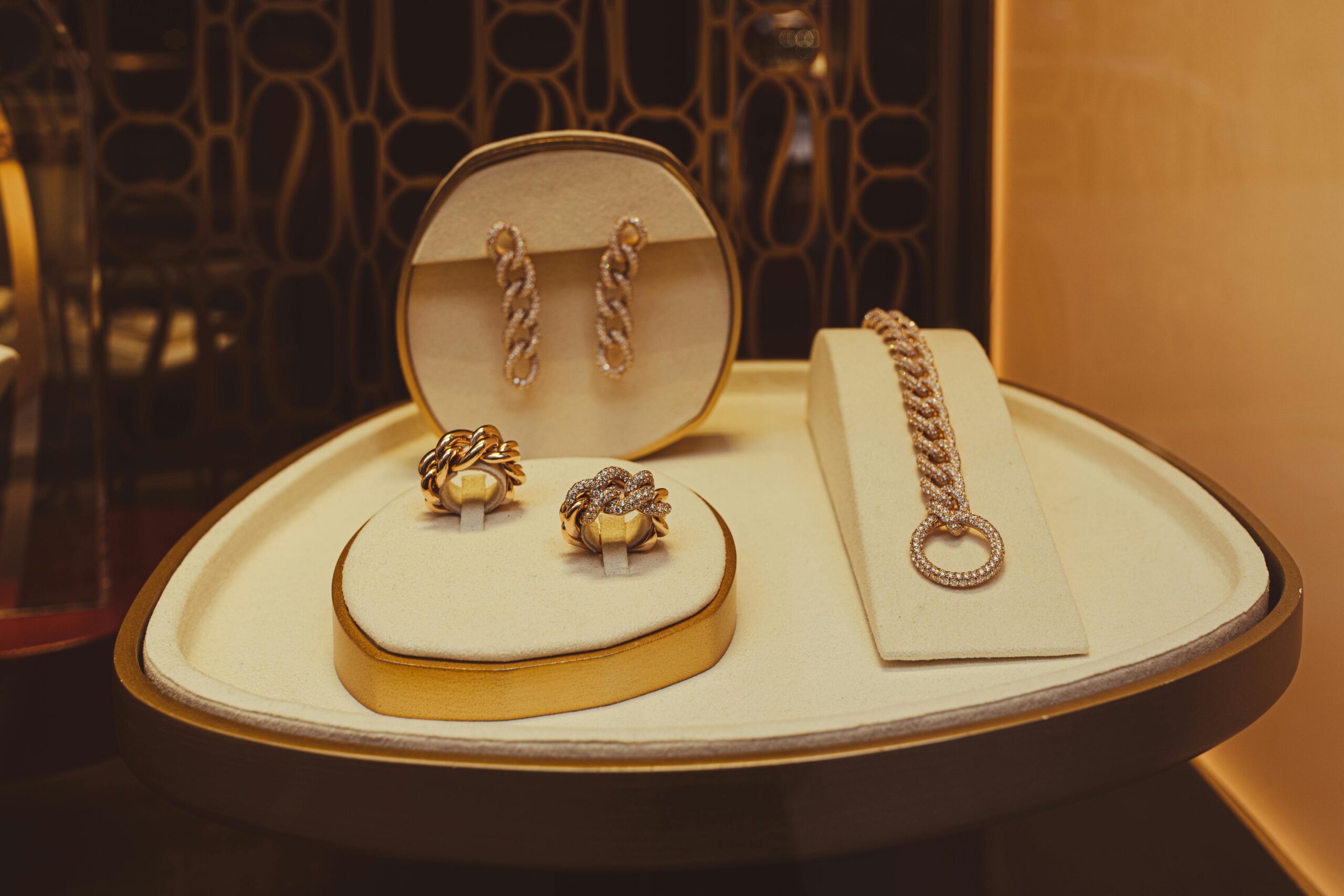 A refined display of elegant gold jewelry pieces in a store setting, showcasing earrings, rings, and a bracelet.