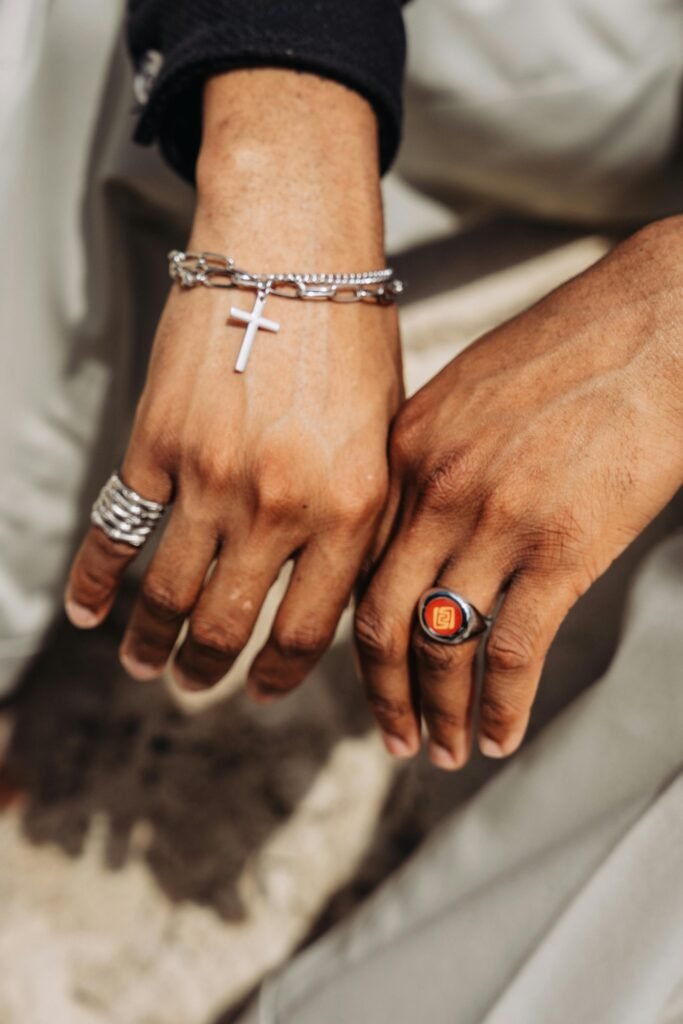 Close-up of a man's hands showcasing stylish rings and a cross bracelet.