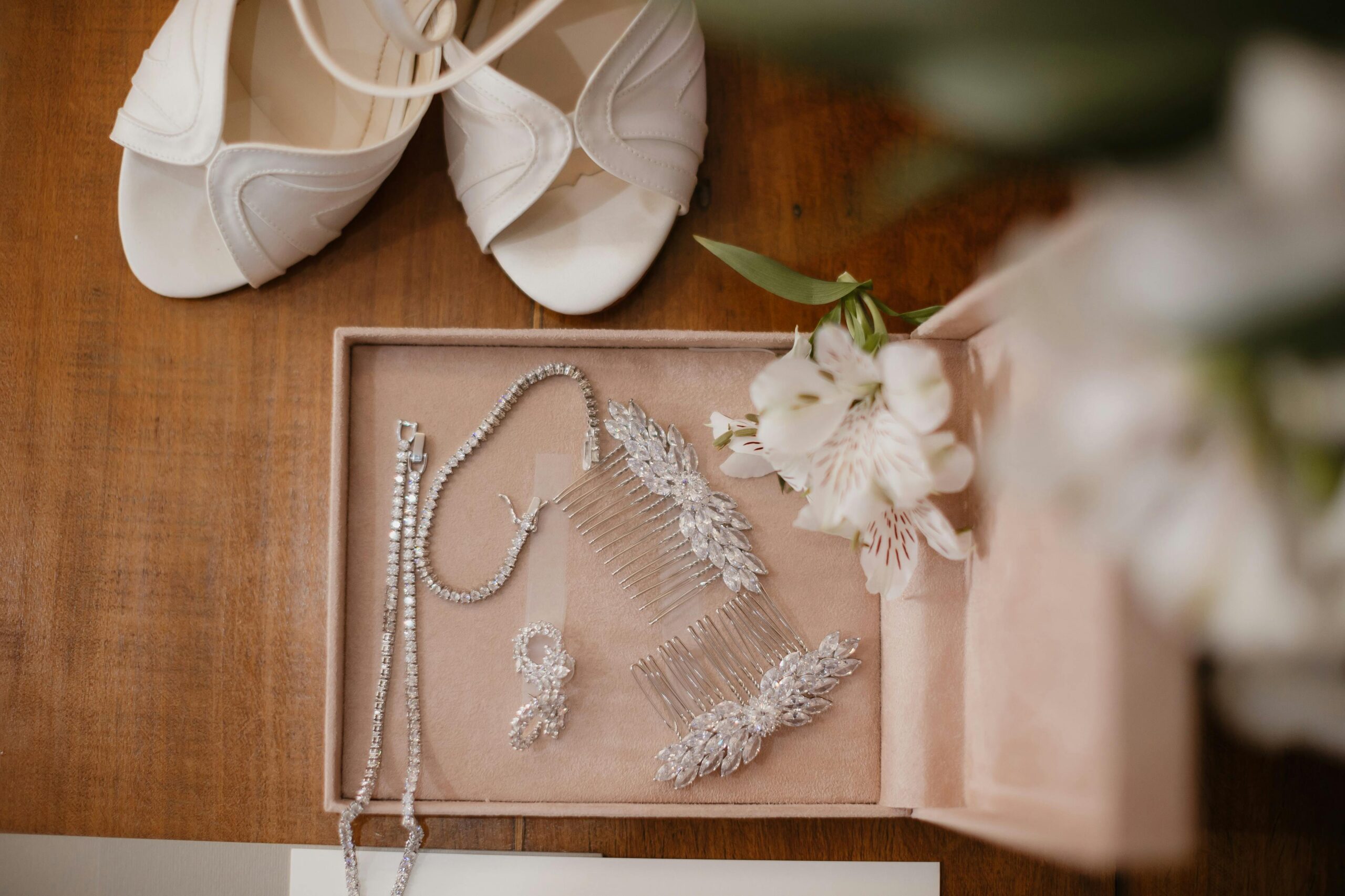 A flat lay of elegant bridal jewelry and white heels, perfect for a wedding day.