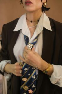 Stylish adult woman accessorizing tie with unique pins, modern fashion.