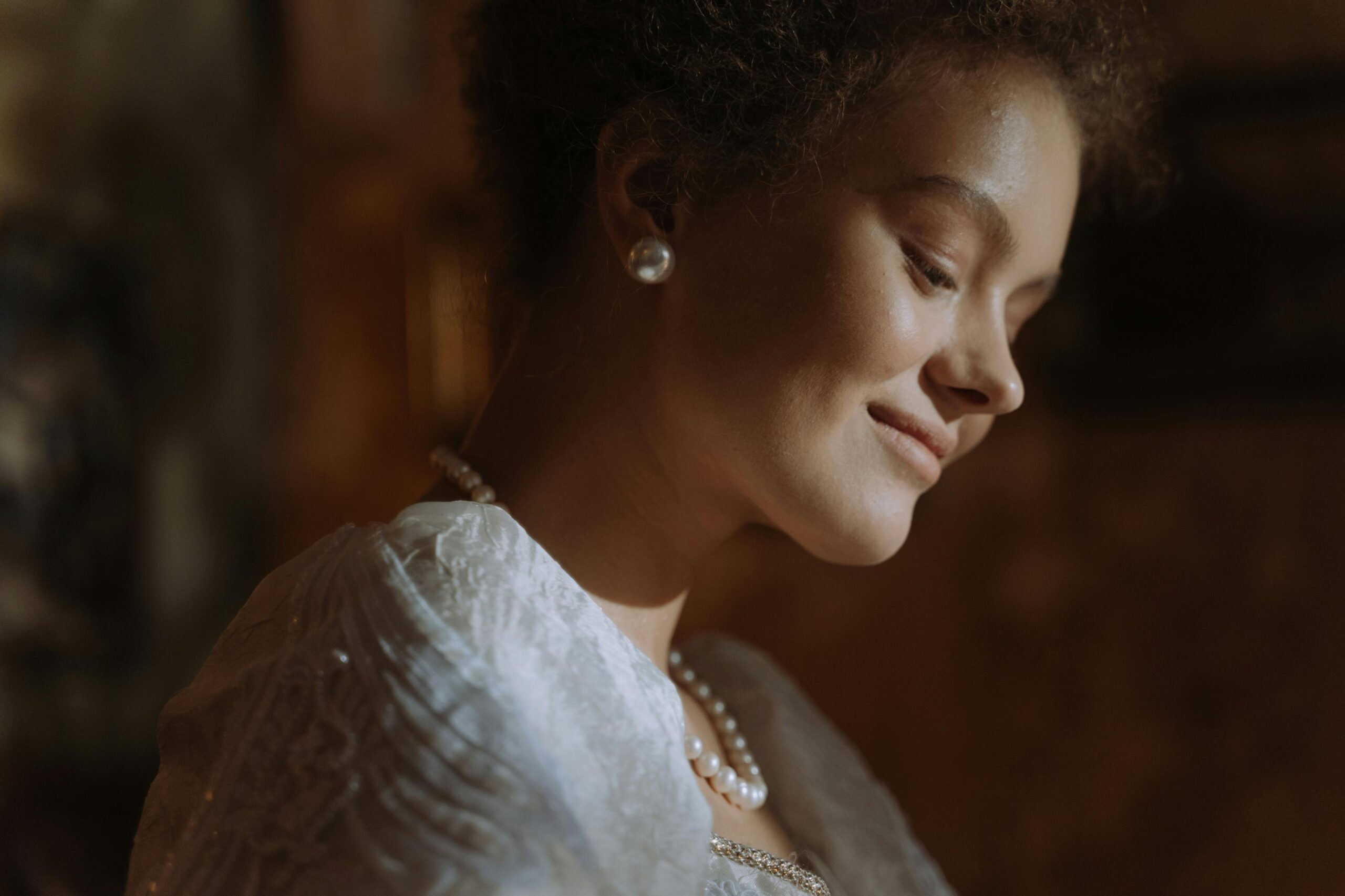 Portrait of an elegant woman adorned with pearls and a gentle smile, radiating warmth.