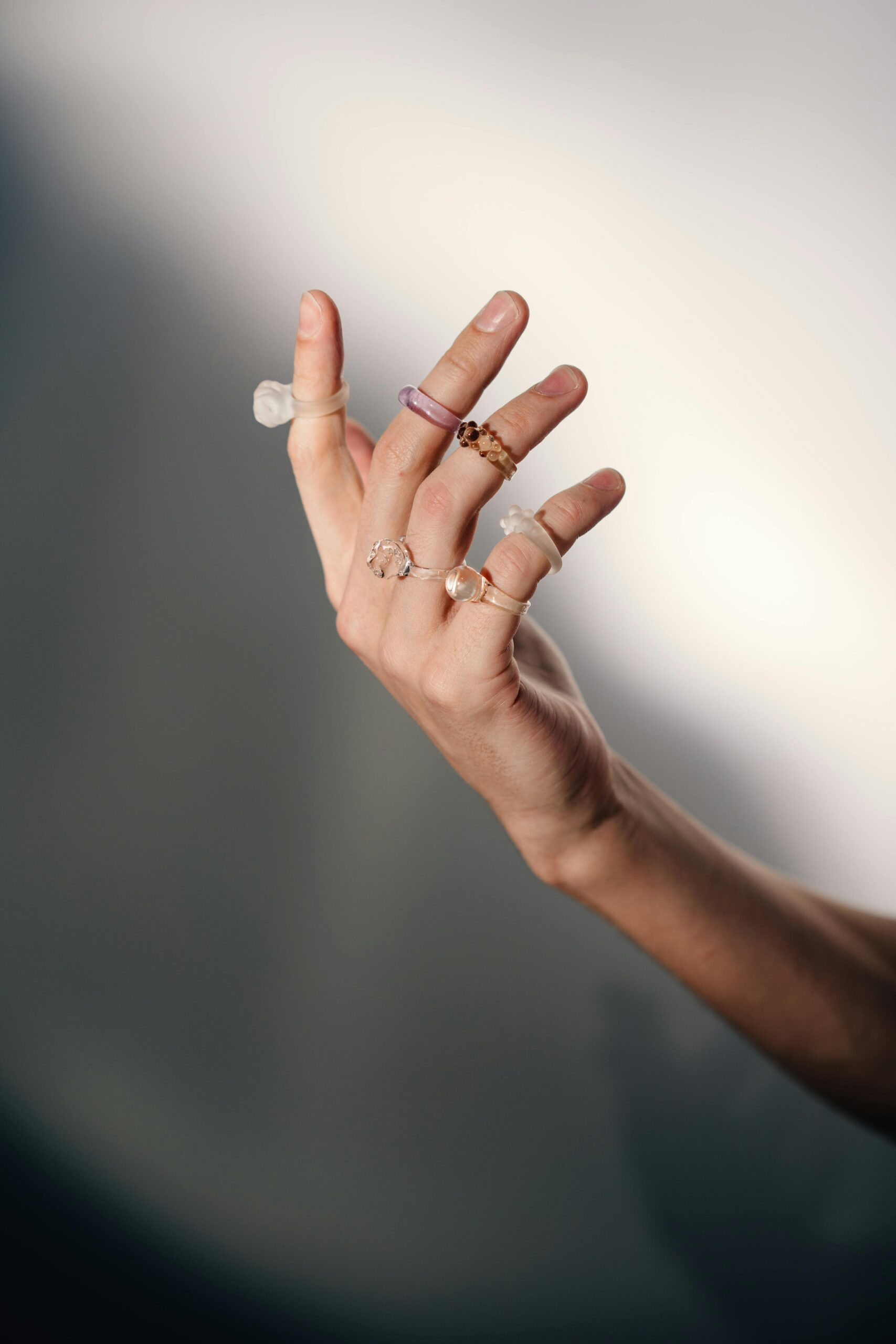 Close-up of a woman's hand adorned with various elegant rings against a blurred background.
