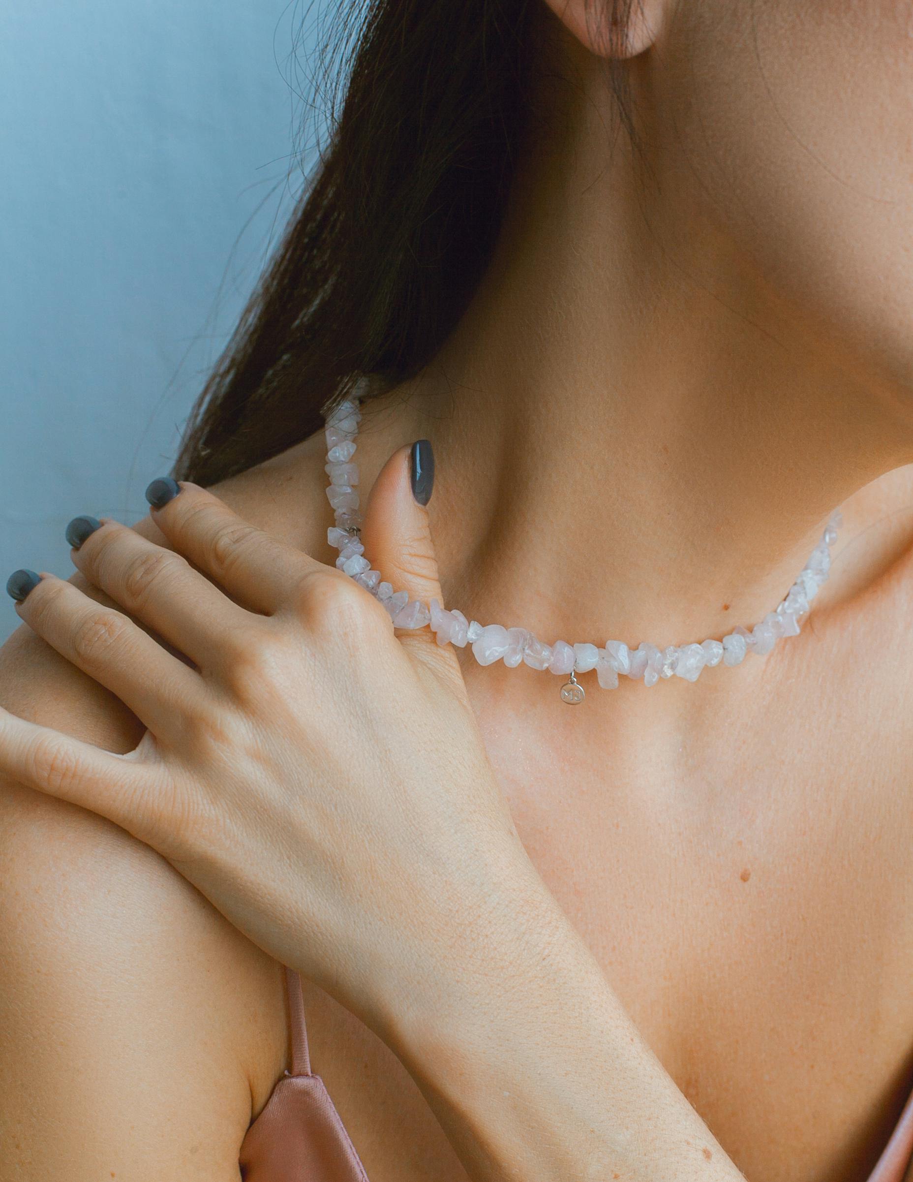 Close-up shot of a woman wearing a delicate stone necklace in a studio setting.