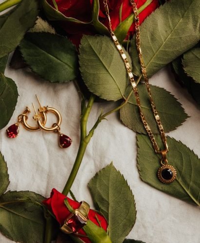 pexels-photo-12002672-12002672 Stylish gold earrings and necklace displayed on red roses over a white sheet, perfect luxury background.